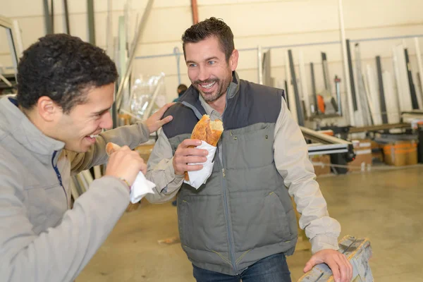 Веселі працівники обідають, їдять бутерброд у майстерні — стокове фото