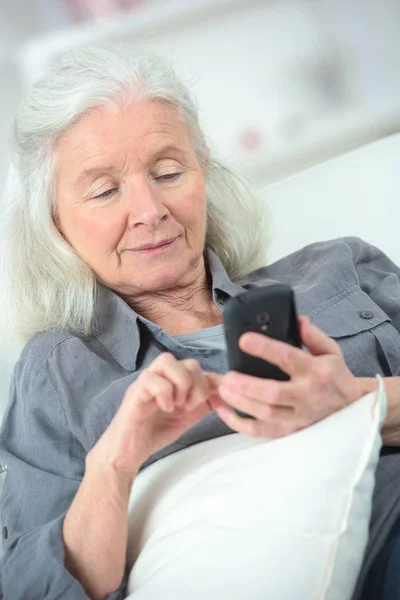 Oude lachende vrouw met mobiele telefoon — Stockfoto