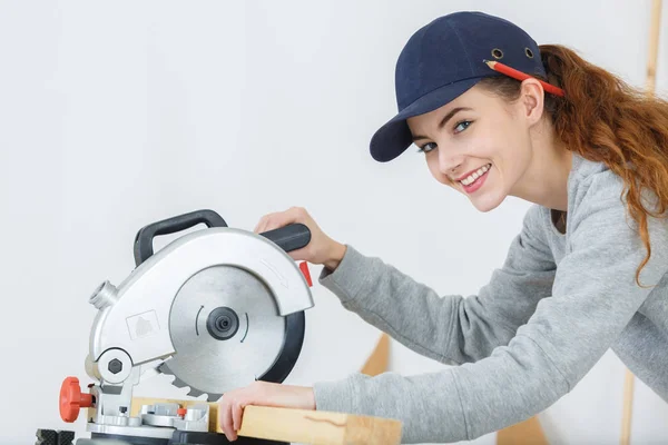 Lycklig kvinna i builder clothers holding cirkelsåg — Stockfoto