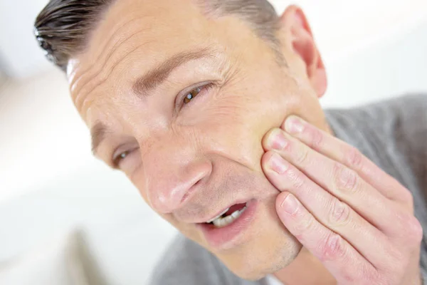 Hombre sosteniendo su mandíbula hinchada expresando un acke dental —  Fotos de Stock