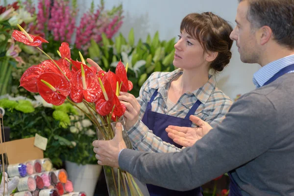 Vrouwelijke bloemisten mannelijke klant te assisteren in het kopen van bloem — Stockfoto