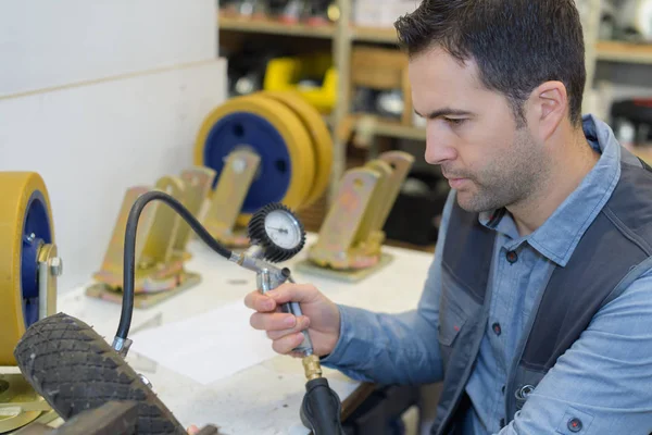 Mann hält Manometer für Reifendruckmessung — Stockfoto