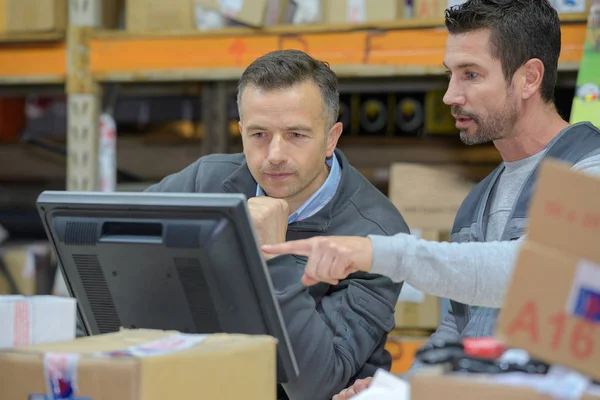 Magazijnmedewerker en manager met behulp van de computer in een magazijn — Stockfoto