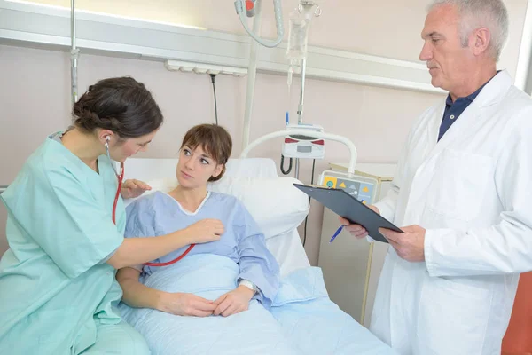 Controlli medici su un giovane paziente disteso in ospedale a letto — Foto Stock