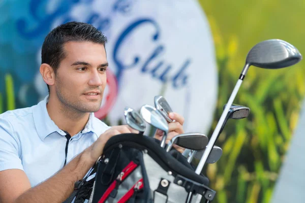 Golfista masculino escolhendo um clube de sua bolsa — Fotografia de Stock