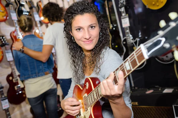 Gitar Store oynamaya çalışan gülümseyen kadın müşteri — Stok fotoğraf