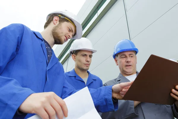 Gruppo di costruttori in hardhat con clipboard — Foto Stock