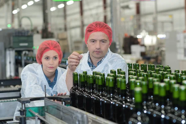 Werknemers onderzoeken wijnflessen op bottelinstallatie — Stockfoto