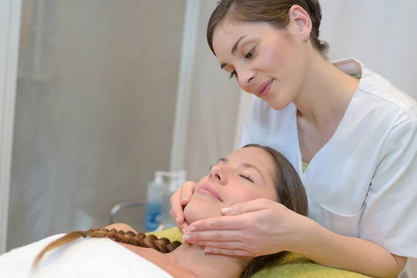 Hermosa joven mujer relajante con masaje facial en el spa de belleza —  Fotos de Stock