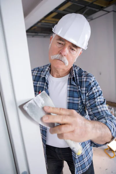 Зрелый мужчина в униформе строителя в помещении — стоковое фото