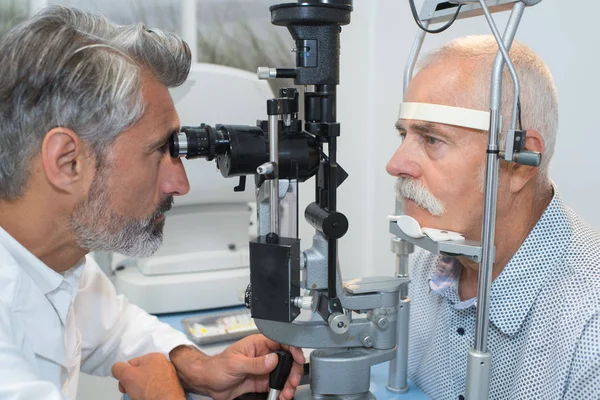 Yaşlı adam gözlerini göz doktoru tarafından muayene yaptırıyor — Stok fotoğraf