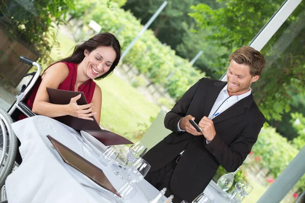 Woman in a wheelchair eating at a restaurant — Stock Photo, Image