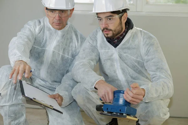 Trabajadores que comprueban dónde hacer lijado de piso —  Fotos de Stock