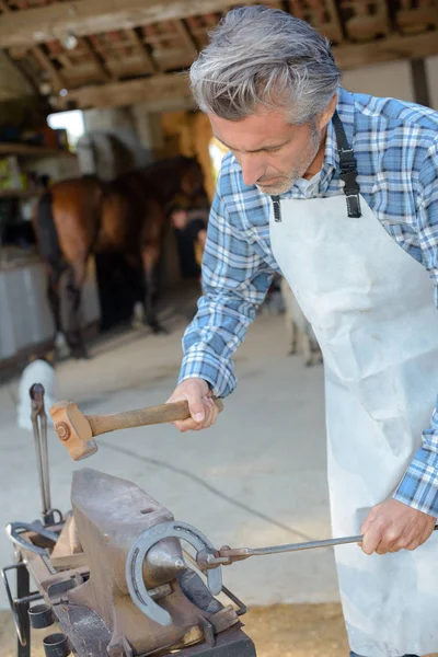 Hovslagare hammering horsehoe och hästsko — Stockfoto