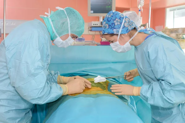 Cirurgiões operar em um paciente em segundo plano Lâmpada cirúrgica — Fotografia de Stock
