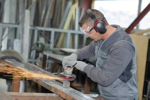 Handwerker sägt Metall mit Scheibenschleifer in Werkstatt — Stockfoto