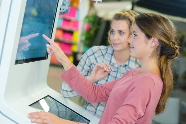 Shop asistent pomáhá zákazníkovi využívat dotykové obrazovky — Stock fotografie