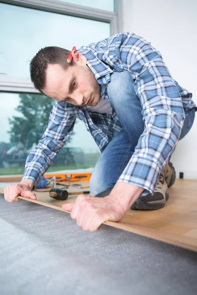 Handyman laying down a carpet in a new house — Stock Photo, Image