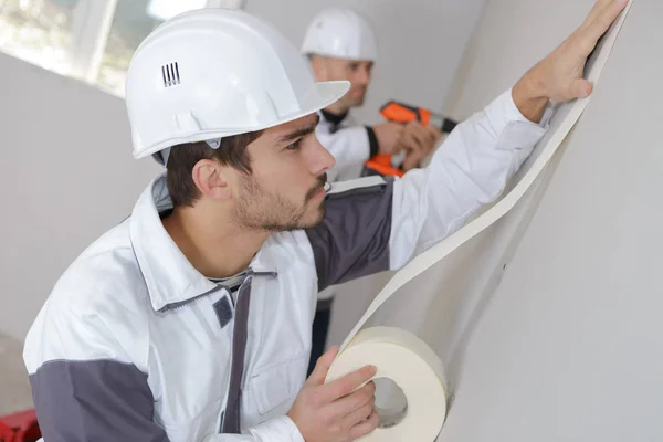 Trabalhador protegendo batten moldagem com fita adesiva antes de pintar — Fotografia de Stock