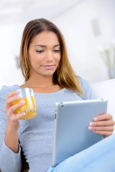 Lady siedział trzymając sok pomarańczowy i komputer typu tablet — Zdjęcie stockowe
