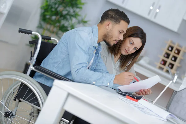 Пара на дому документ для чтения, человек в инвалидной коляске — стоковое фото