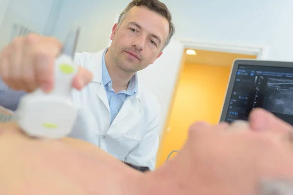 Hombre mayor siendo escaneado en el consultorio médico — Foto de Stock