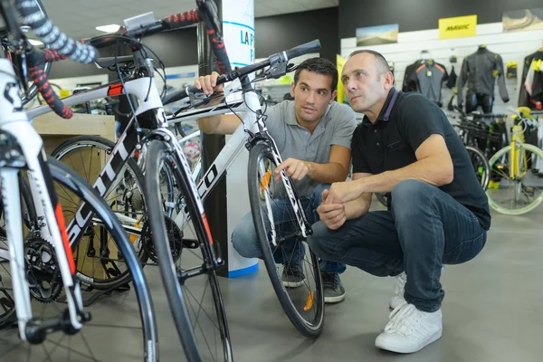 Homem verifica bicicleta com assistente antes de comprar na loja — Fotografia de Stock