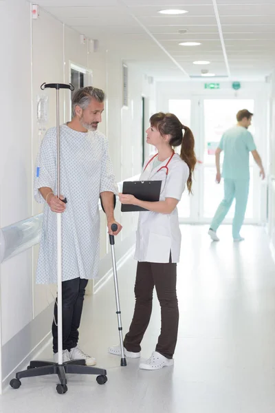 Patient using cane while looking at female doctor — Stock Photo, Image