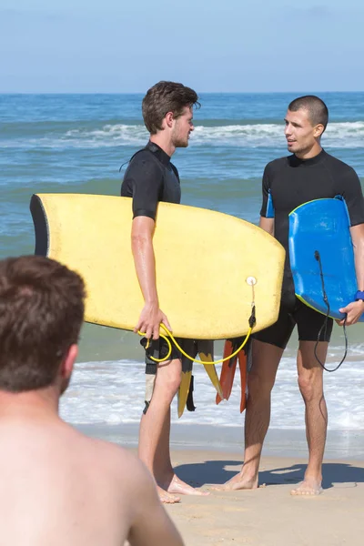 Surfisti che camminano portando a bordo in spiaggia — Foto Stock