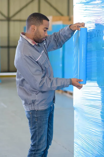 Arbeiter wickeln Waren mit Plastik ein — Stockfoto