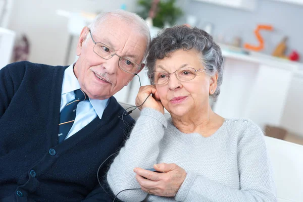 Betagtes Paar teilt sich Kopfhörer und hört Radio — Stockfoto