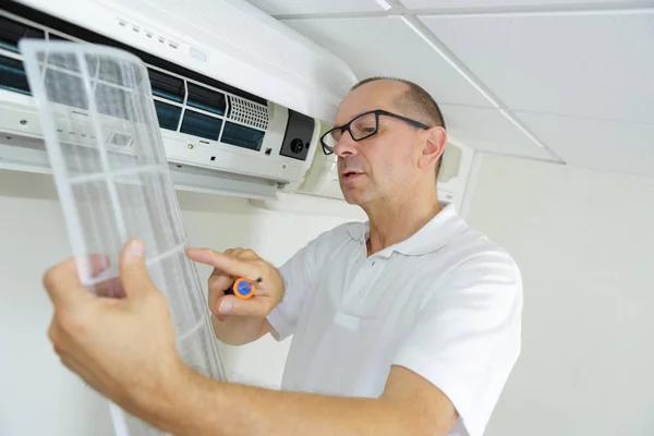 Medelålders man justera luftkonditioneringssystem — Stockfoto