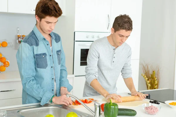 Tres amigos varones haciendo pizza en la cocina juntos —  Fotos de Stock