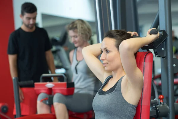 Adatta donna utilizzando la macchina pesi per le braccia in palestra — Foto Stock