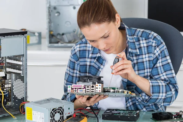 Женщина-электронист, ремонтирующая материнскую плату компьютера — стоковое фото