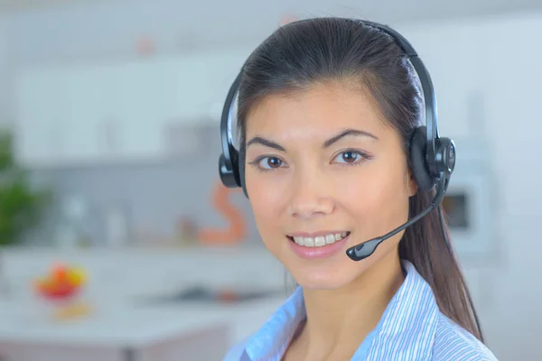 Amichevole sorridente giovane operatore telefonico donna al suo posto di lavoro — Foto Stock