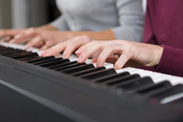 4 руки играют на фортепиано близко — стоковое фото