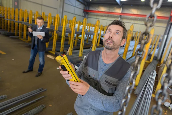 Trabalhador olhando para cima no armazém enquanto segurando dispositivo digital — Fotografia de Stock