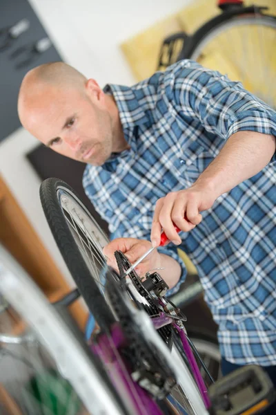 Hombre trabajando en taller de reparación de bicicletas — Foto de Stock