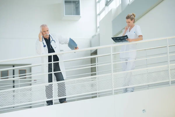 Médico y enfermera en el pasillo del hospital descansando contra el balcón —  Fotos de Stock