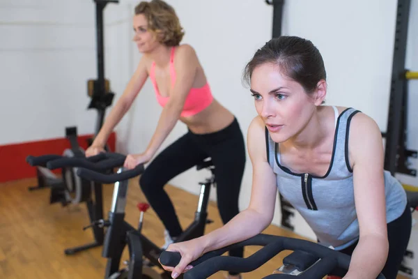 Zwei hübsche Frauen beim Turnen auf Fahrrädern im Fitnessstudio — Stockfoto