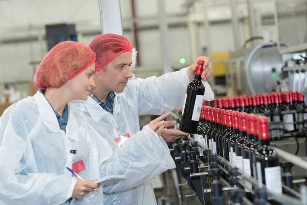 Scientist speaking to his colleague holding wine bottle — Stock Photo, Image