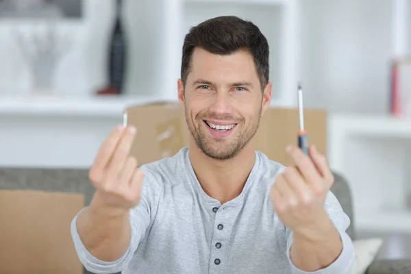 Hombre feliz mostrando un destornillador y un tornillo — Foto de Stock