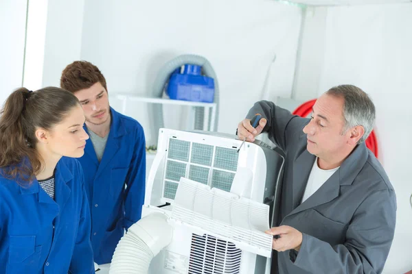 Les étudiants professionnels apprennent la réparation de la climatisation auprès d'un instructeur expérimenté — Photo