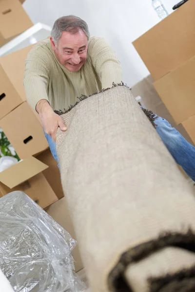 Hombre moviendo un rollo de alfombra pesada — Foto de Stock