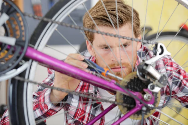 Schöner junger Mann erneuert die Kette des Fahrrads — Stockfoto