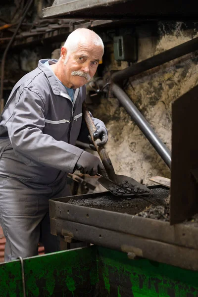 Senior blacksmith removing ashes — Stock Photo, Image