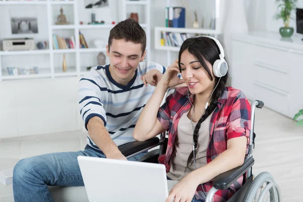 Ongeldige meisje op de rolstoel met laptop en haar vriend — Stockfoto