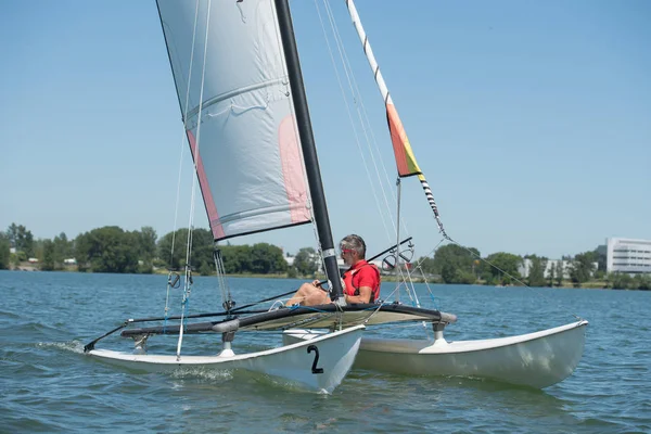 Katamaran-Segelboot und Mann an einem sonnigen Tag — Stockfoto