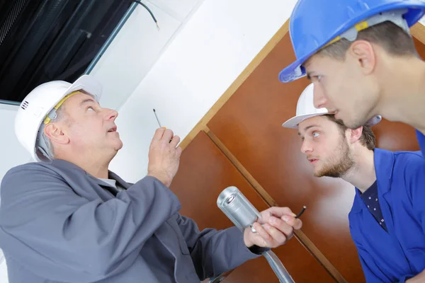 Електрик ремонтник і студенти фіксують кондиціонер в будинку — стокове фото